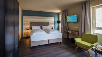 A hotel room with a bed, a desk, a chair, a TV, and a window.