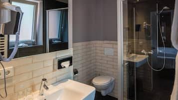 Une salle de bain moderne avec un lavabo blanc, des toilettes et une douche à parois de verre.