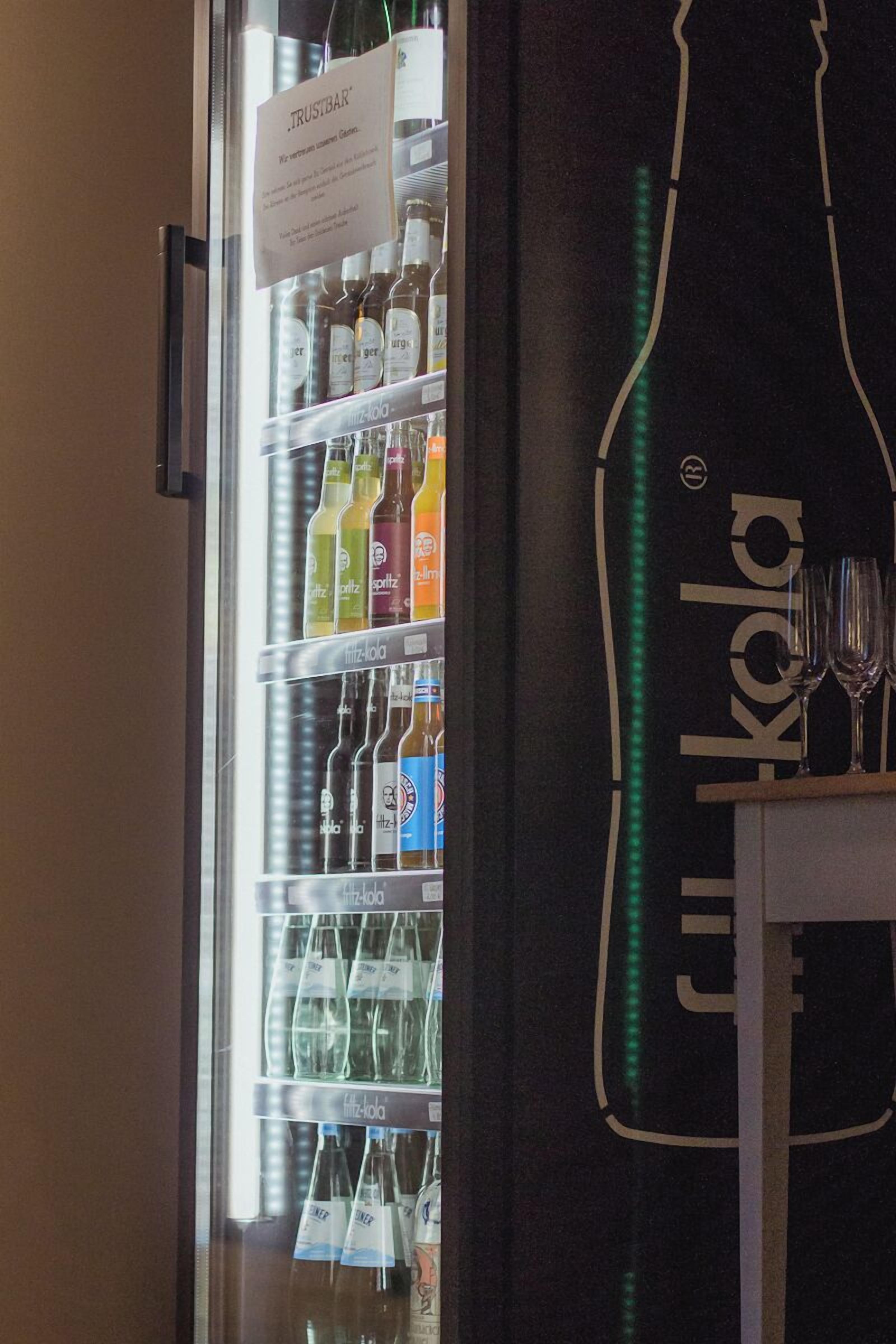 Ein Kühlschrank voller Getränke und ein Schild mit der Aufschrift 'TRUSTBAR'.