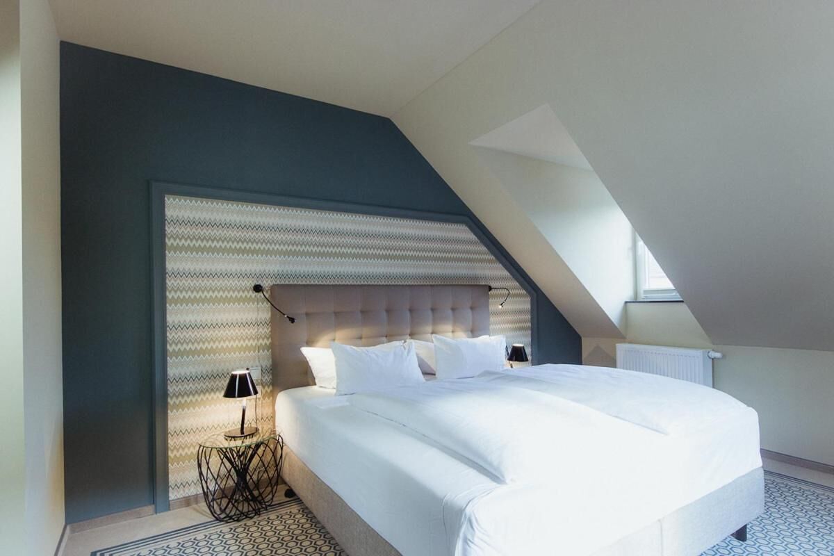 Un dormitorio moderno con una cama grande, un diseño de techo original y un suelo estampado.