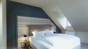 Un dormitorio moderno con una cama grande, un diseño de techo original y un suelo estampado.