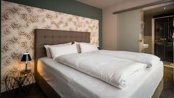 Ein Doppelbett mit einem geblümten Kopfteil, ein Nachttisch mit einer Lampe und eine Wand mit Muster.