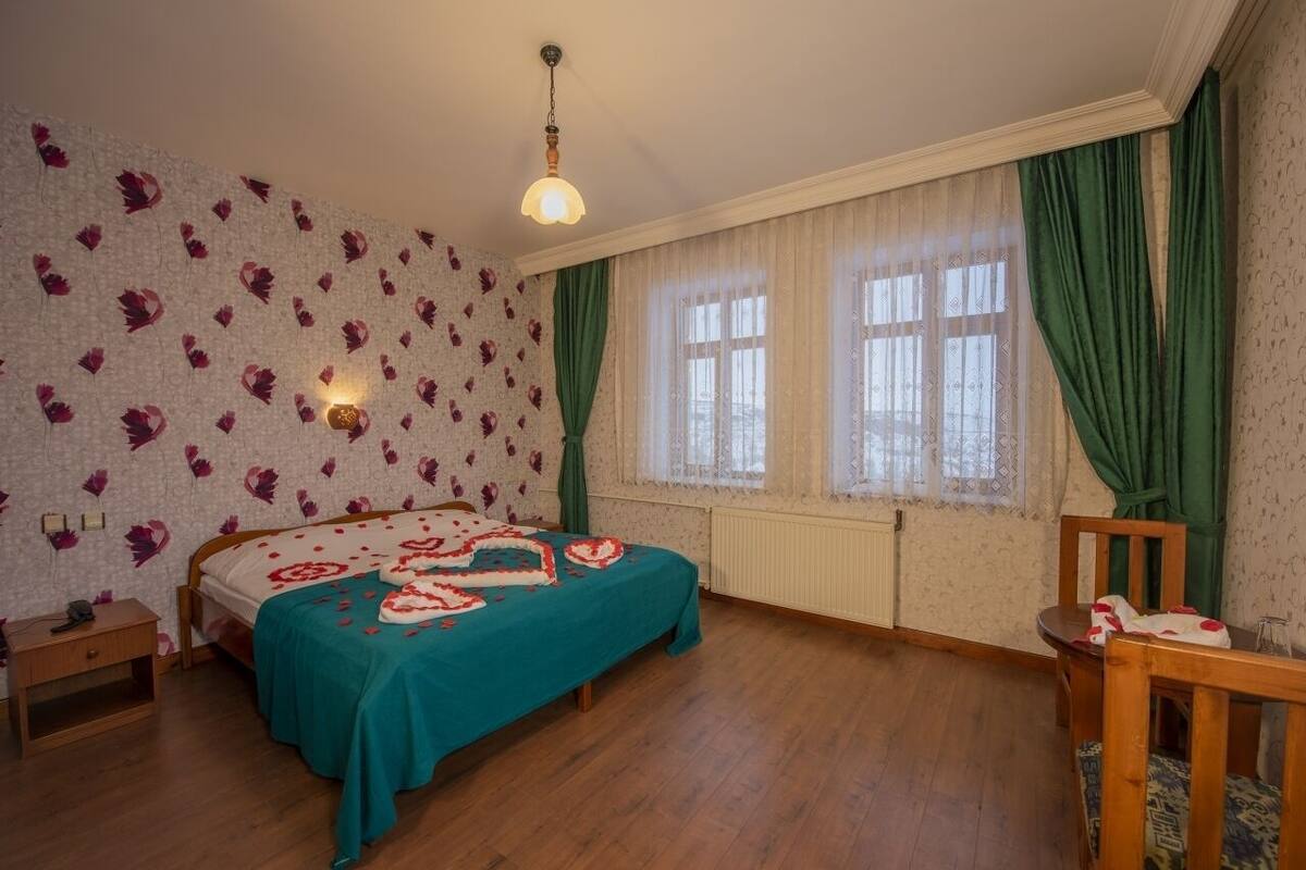 A bedroom with a bed, a nightstand, a chair, and a window with curtains.