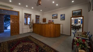 Een receptie met een houten toonbank, een vloerkleed en een hond in een kar.