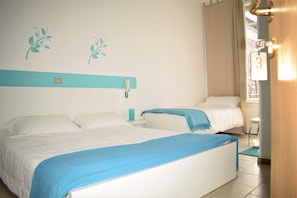 A hotel room with two beds, a nightstand, a lamp, and a view of the outside. - Hotel Canarco (Viareggio)