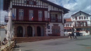 Un edificio tradicional con un balcón, una bandera y una escalera que lleva a la entrada.