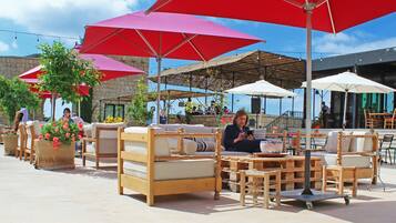 Outdoor seating with red umbrellas, wooden furniture, and potted plants.