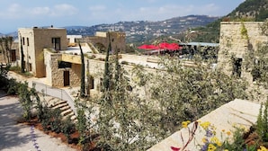 A stone building with a staircase and a view of a city in the distance. - Bkerzay (Deir Dourite)