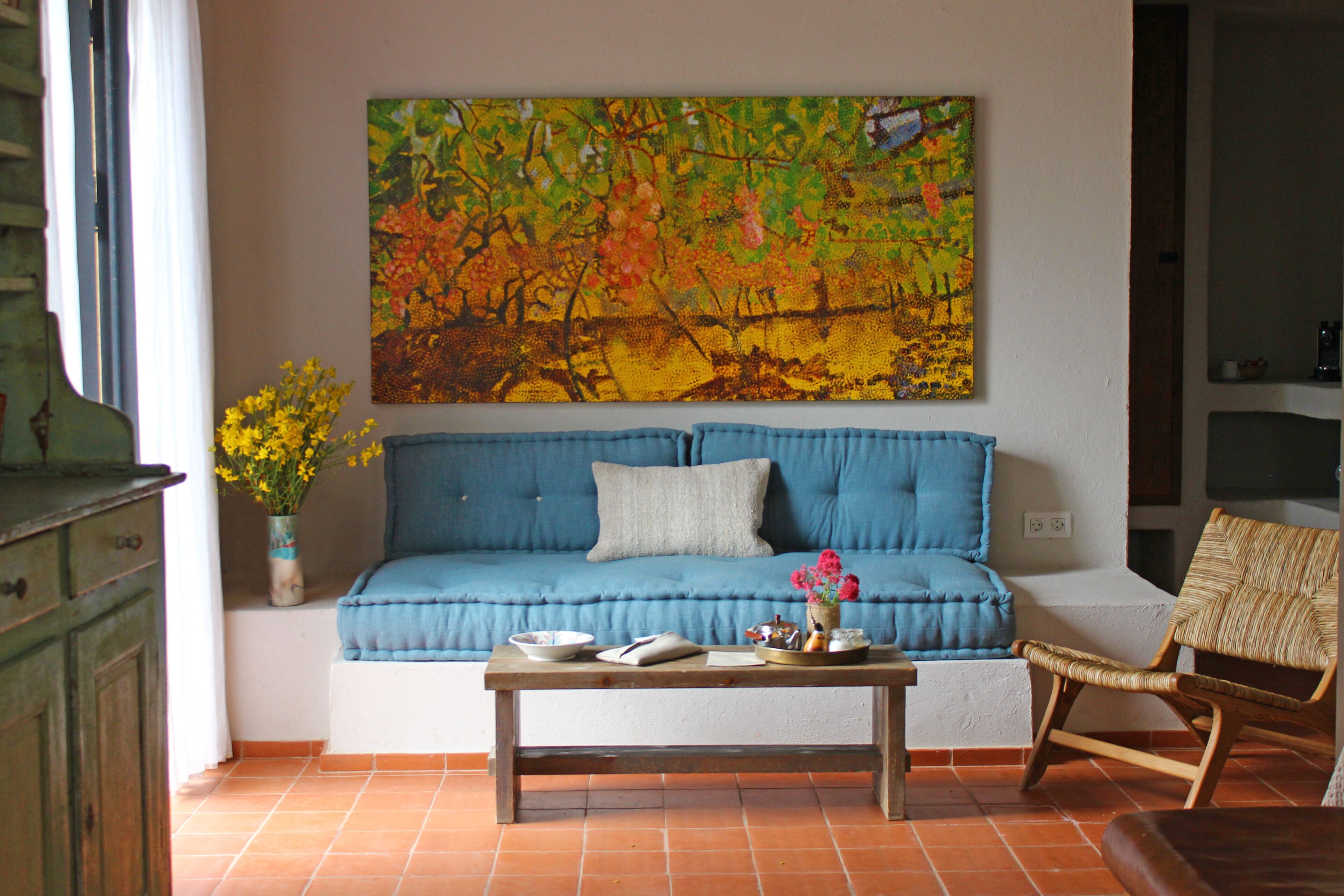 A living room with a blue sofa, a wooden coffee table, and a wicker chair.