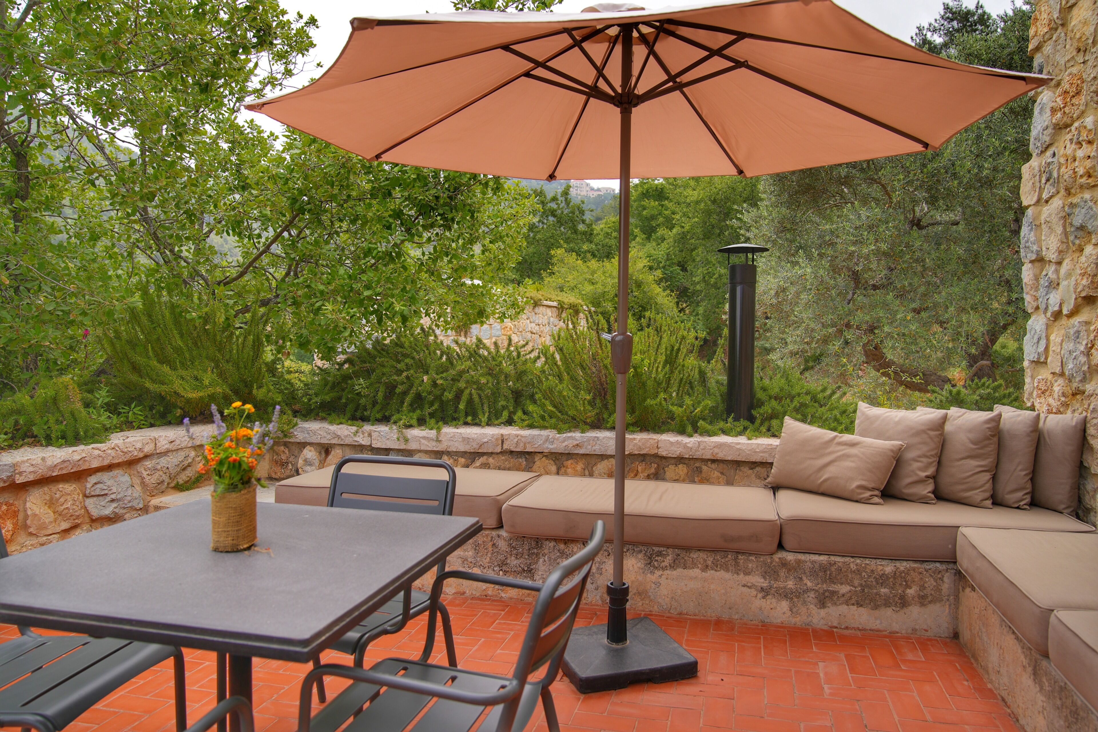 An outdoor patio with a table, chairs, a cushioned bench, and a large umbrella.