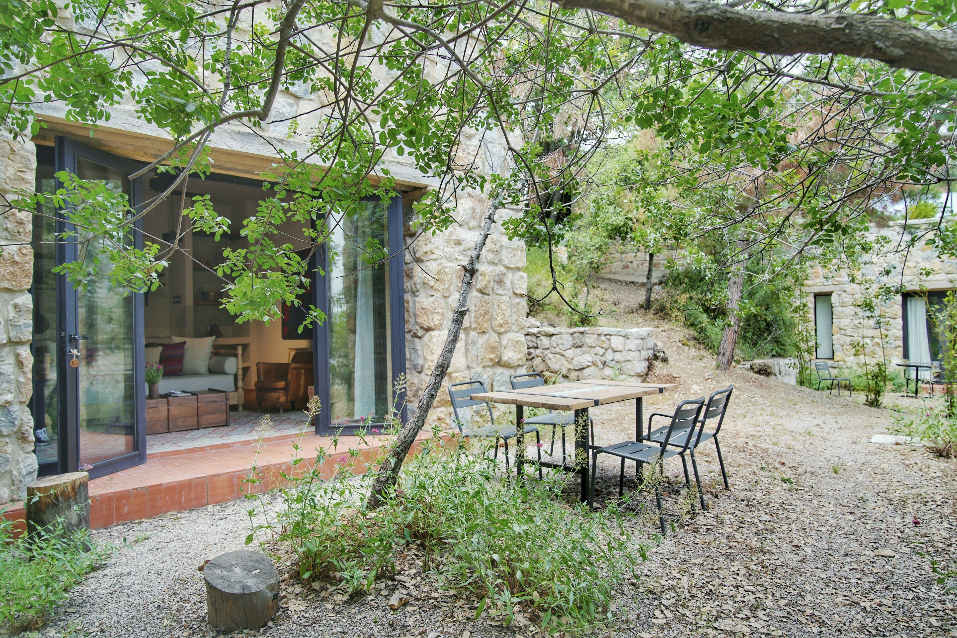 A stone building with a glass-enclosed patio, outdoor seating, and a view of the interior.