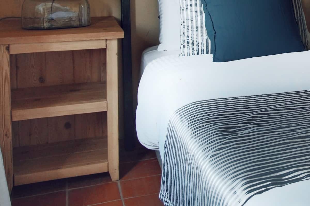 Ein Schlafzimmer mit einem Bett, einem Nachttisch, einem gerahmten Bild und einem Kopfteil.