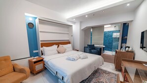 Une chambre d’hôtel moderne équipée d’un lit, d’une table de chevet, d’une chaise, d’un bureau et d’un espace douche.