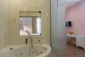 Un baño moderno con una bañera independiente, un espejo y un televisor en la habitación contigua.