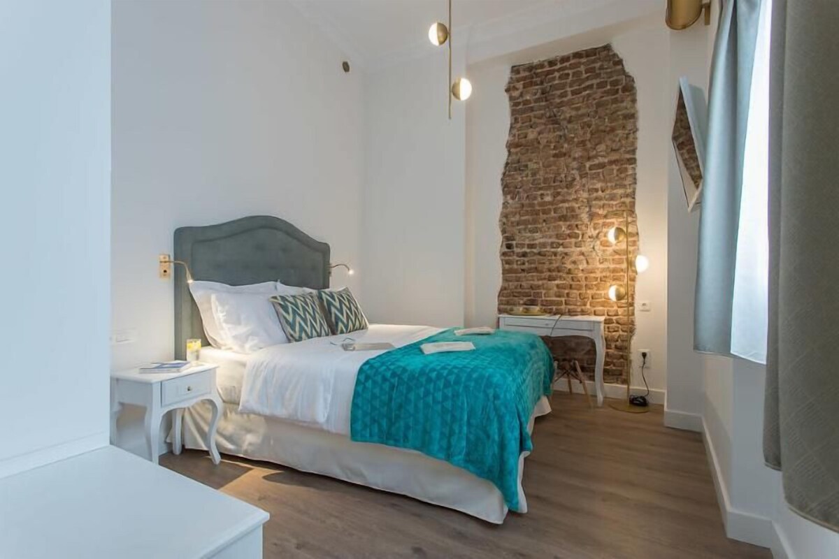 Een slaapkamer met een bed, nachtkastje en bureau met stoel.