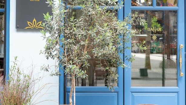 Une porte bleue avec une enseigne indiquant « BAHAR BOUTIQUE HOTEL » et un pot de fleurs placé devant.