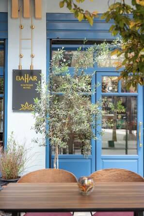 Una puerta azul con un letrero que dice 'BAHAR BOUTIQUE HOTEL' y una planta en maceta al frente.