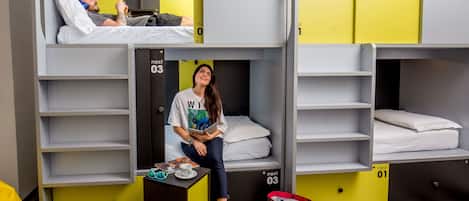 A dormitory room with bunk beds, a desk, and a chair.