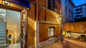 A hotel entrance with a wooden door, a staircase, and a small outdoor seating area with a table and chairs. - Free Hostels Roma (Rome)
