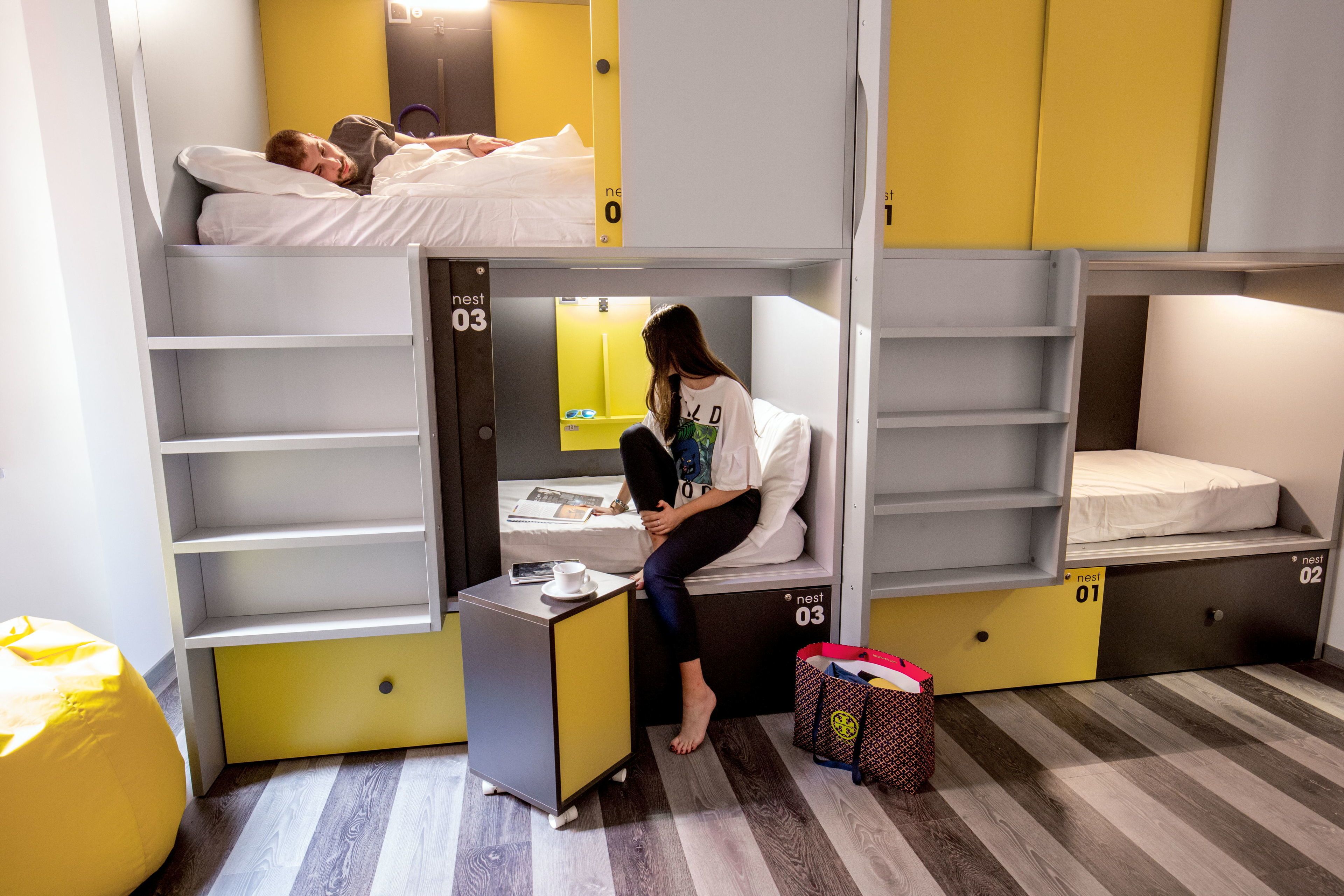 A dormitory room with bunk beds, a desk, and a chair.
