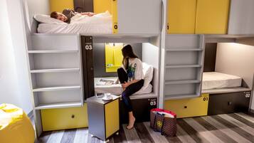 Een studentenkamer met stapelbedden, een bureau en een stoel.