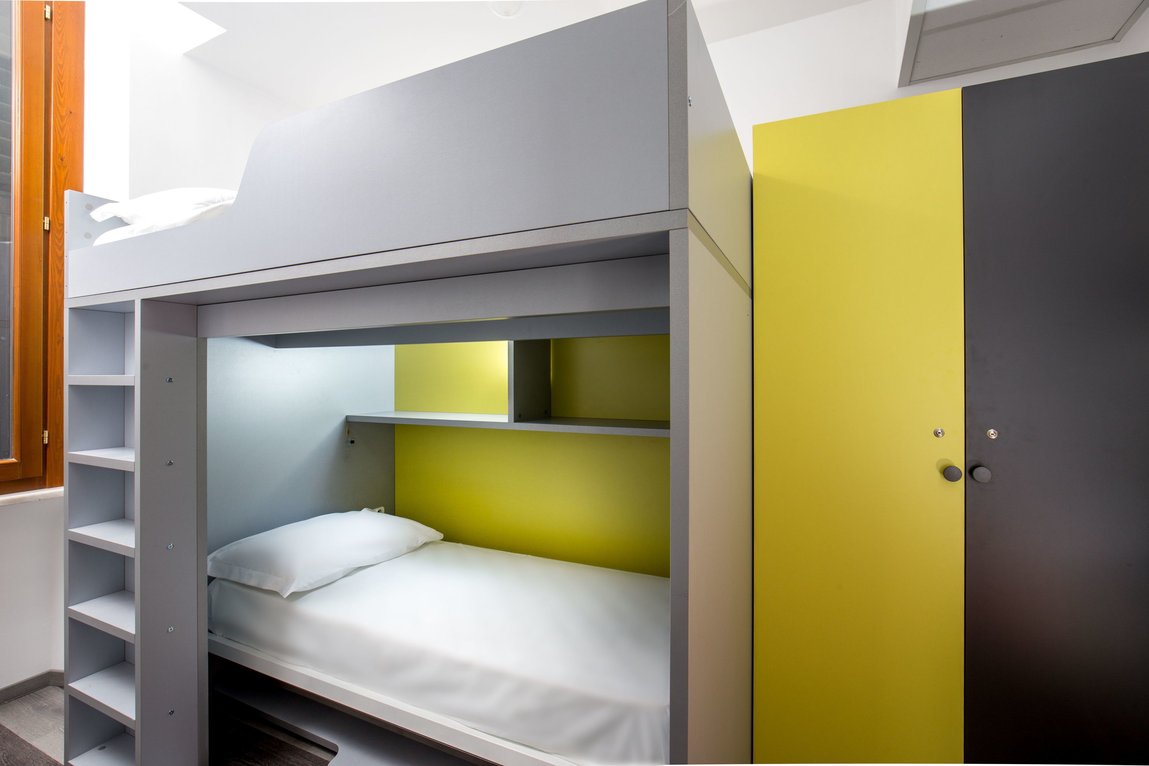 A bunk bed with a white mattress and a yellow headboard.