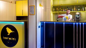 A bar area with a bartender, a neon sign, and shelves with bottles.