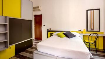 A modern hotel room with a bed, a desk, a chair, and a large wardrobe.