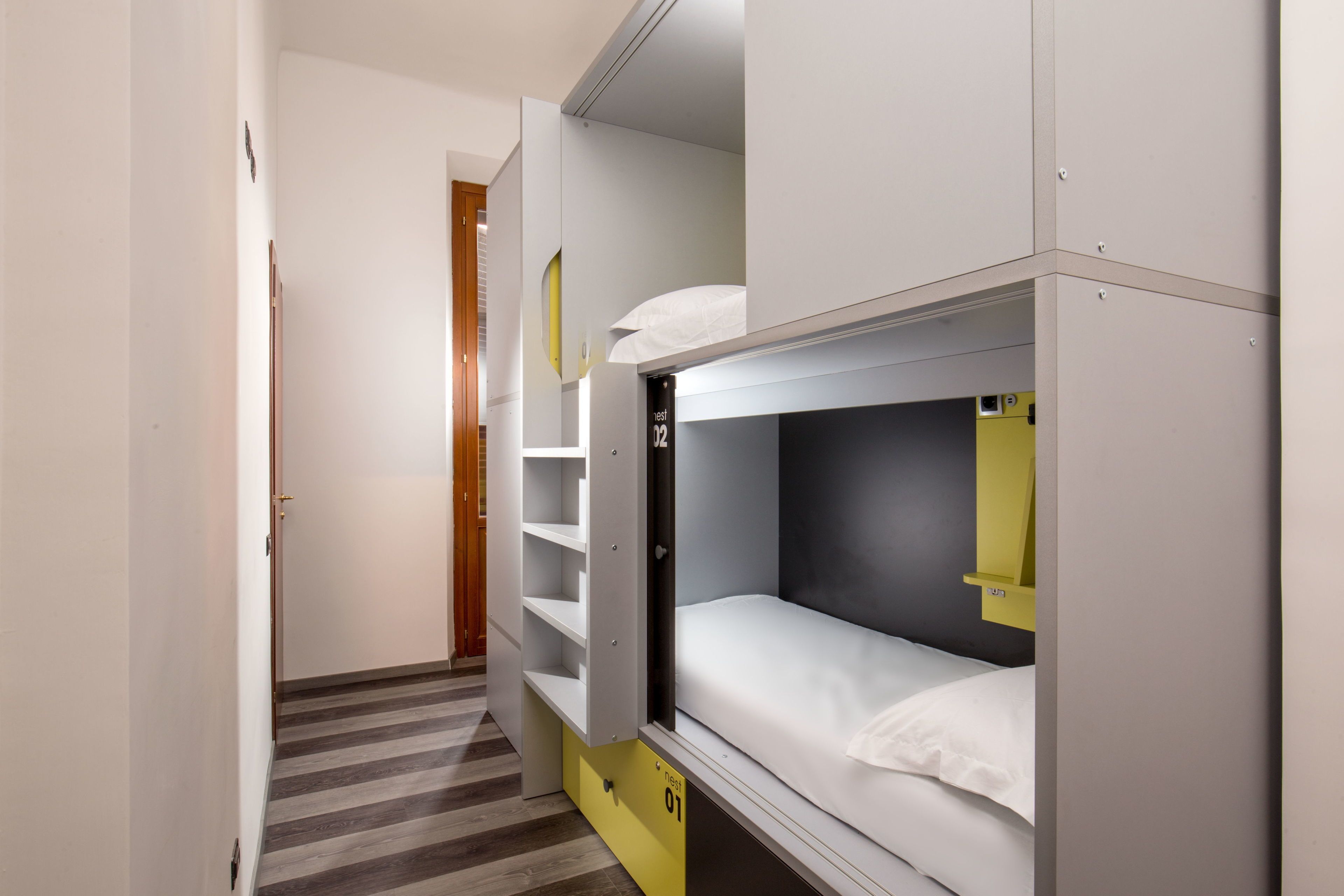Una habitación de hotel pequeña con literas, un escritorio y un armario.
