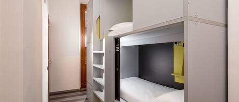 A compact hotel room with bunk beds, a small desk, and a wardrobe.
