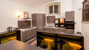A modern kitchen with a central island, bar stools, and built-in appliances. - Free Hostels Roma (Rome)