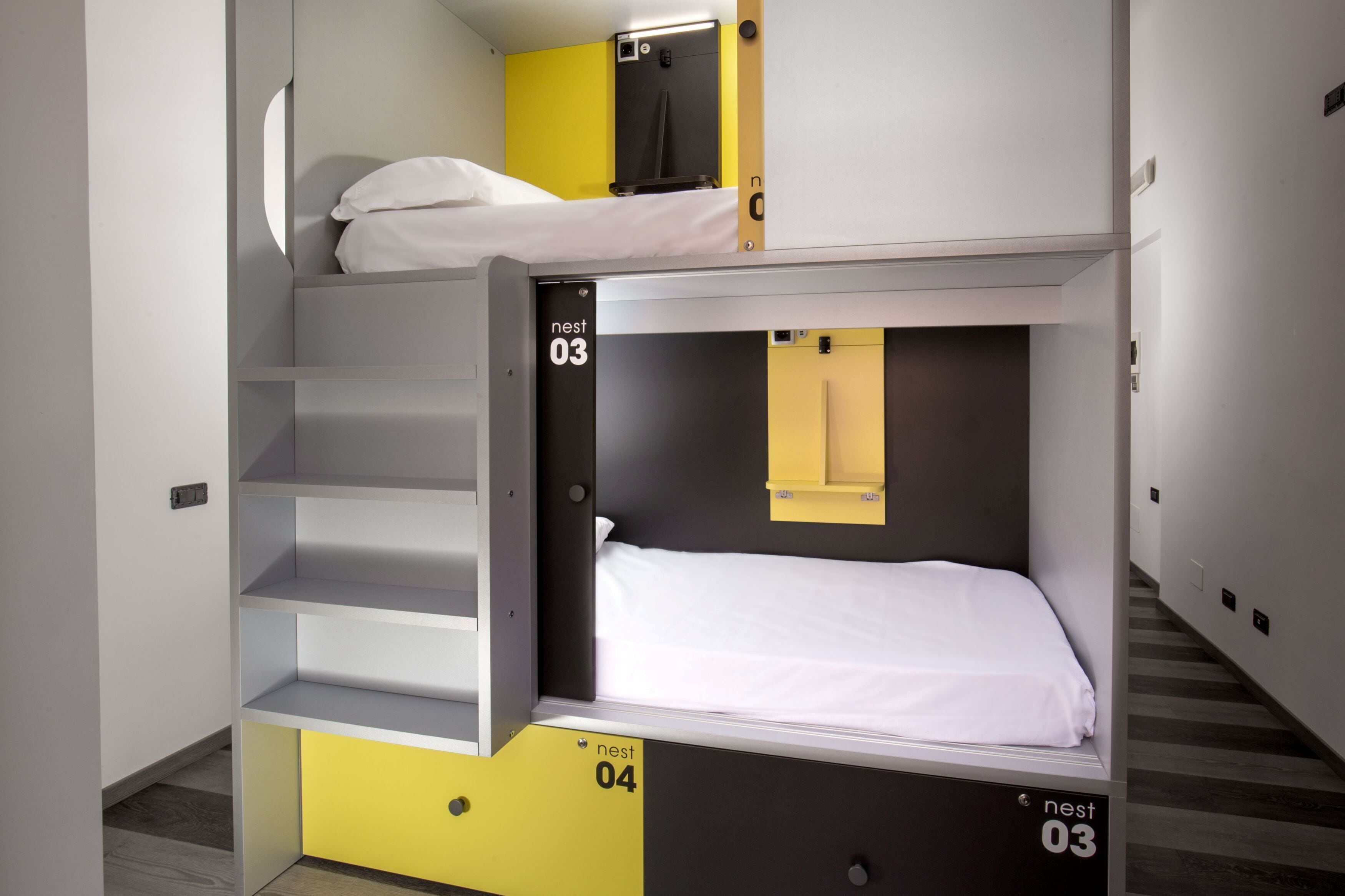 Camera con letto a castello, scomparti identificati con l'etichetta 'nest 03' e 'nest 04', un piccolo specchio e un armadietto giallo.