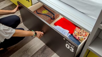 Una persona abre un cajón en una habitación con piso a rayas y un armario amarillo al fondo.