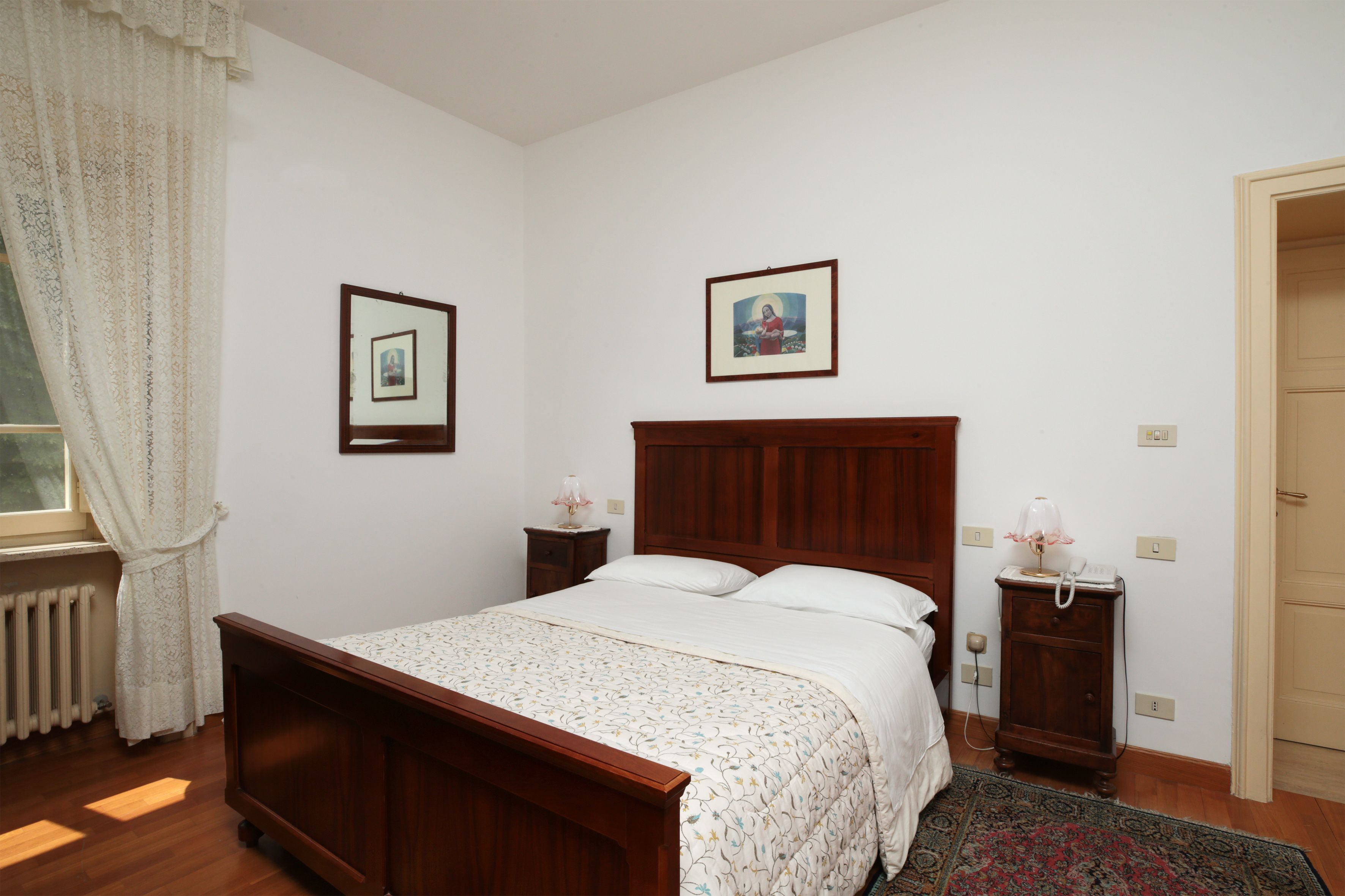 Un dormitorio con cama de madera, una mesita de noche, una lámpara y un cuadro enmarcado en la pared.
