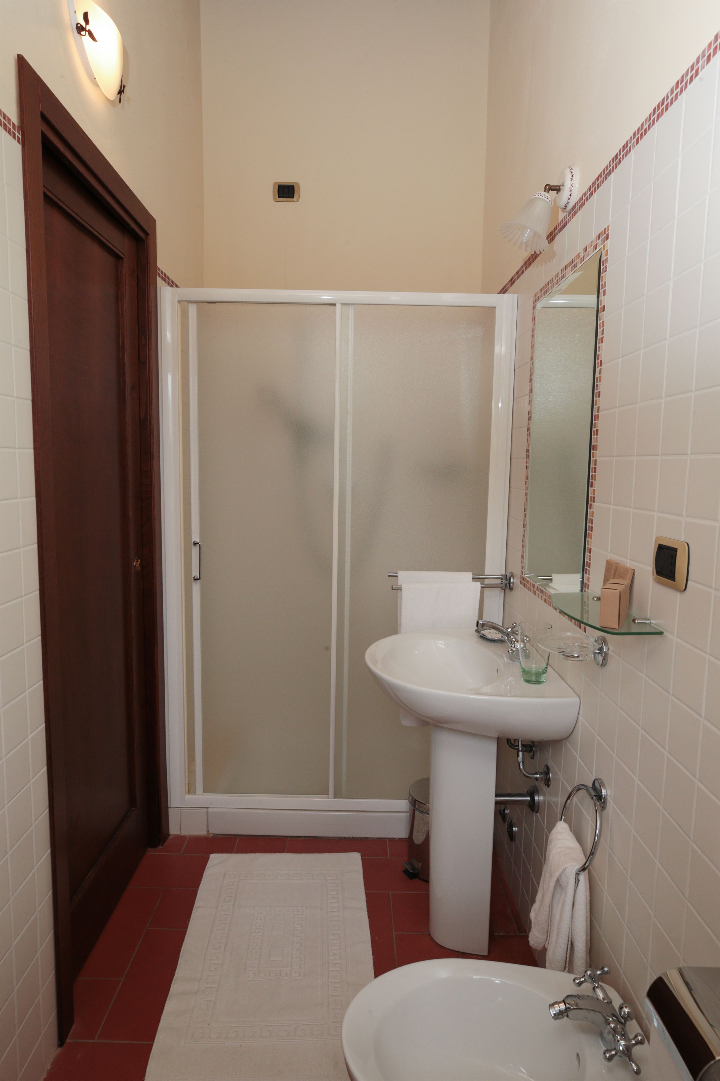 Un bagno con doccia, lavandino e specchio.