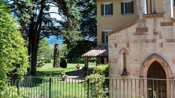 A stone building with a bell tower, surrounded by lush greenery and trees. - Il Castellaro Country House (Perugia)
