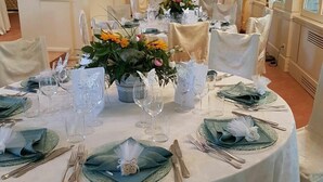 A formal dining room with round tables set for a meal, featuring green tablecloths, white chairs, and floral centerpieces. - Il Castellaro Country House (Perugia)