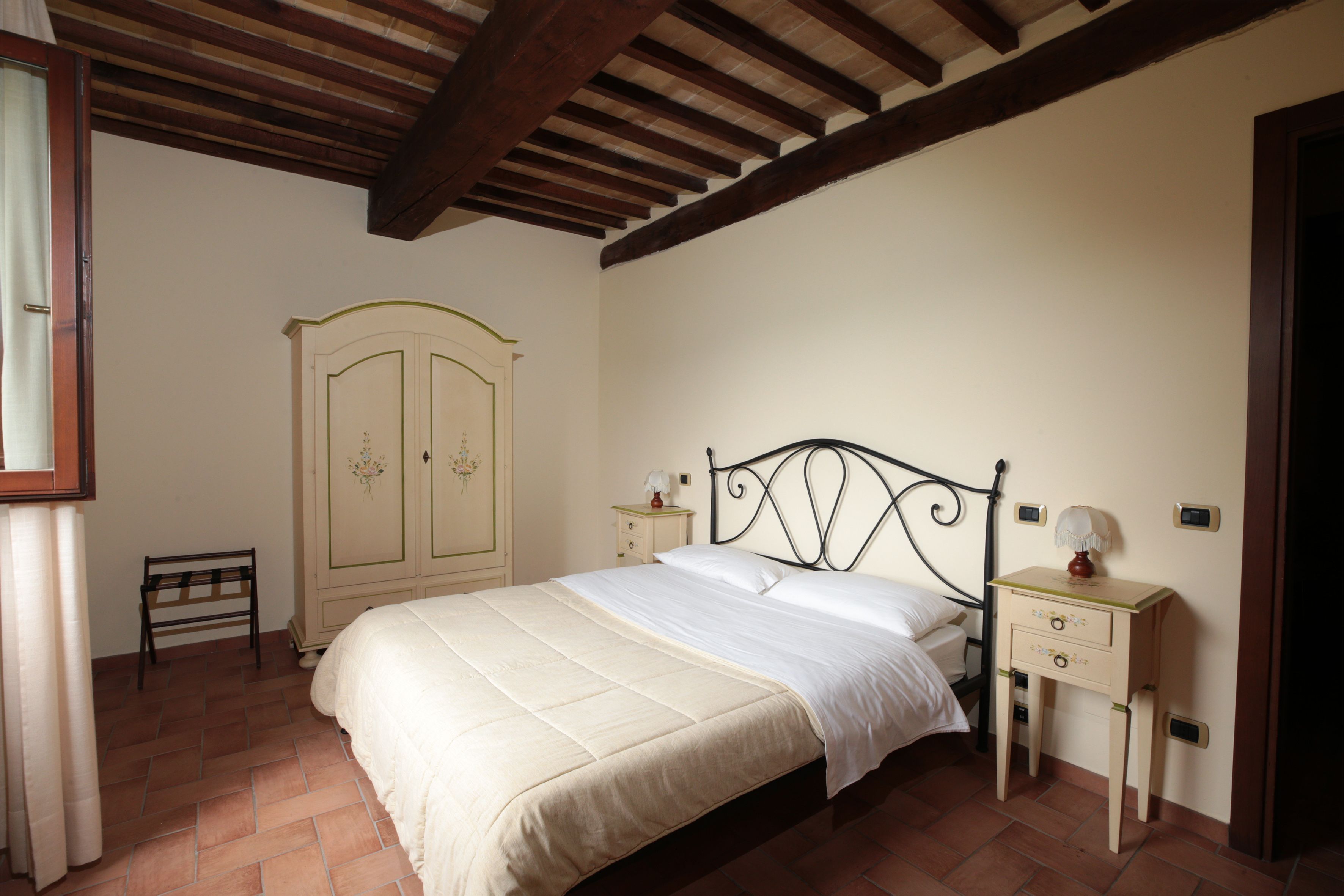 Un dormitorio con una cama, una mesita de noche, un armario y un banco.