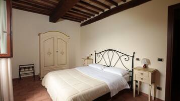 Un dormitorio con una cama, una mesita de noche, un armario y un banco.