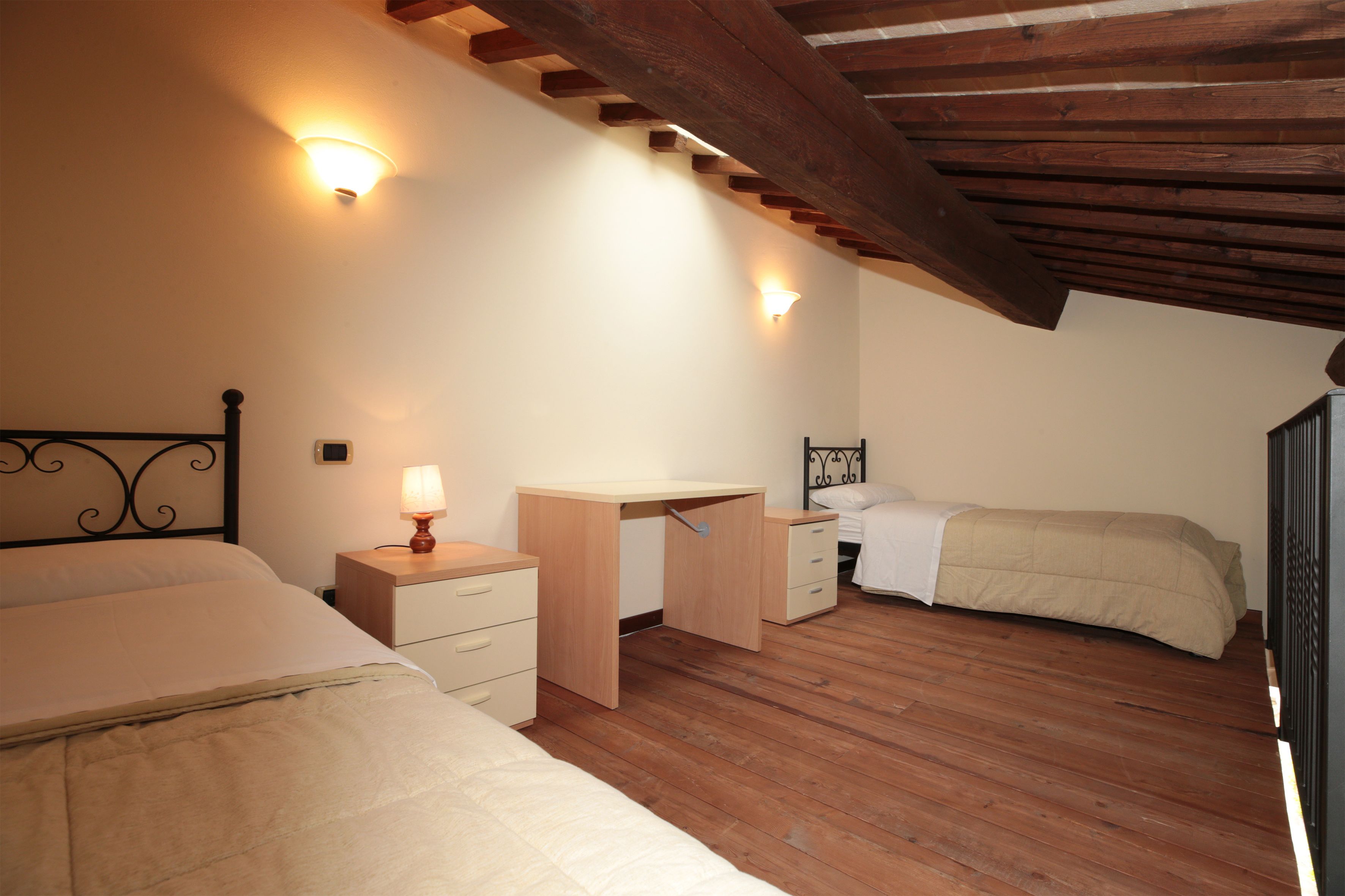 A bedroom with two beds, a desk, and a nightstand.