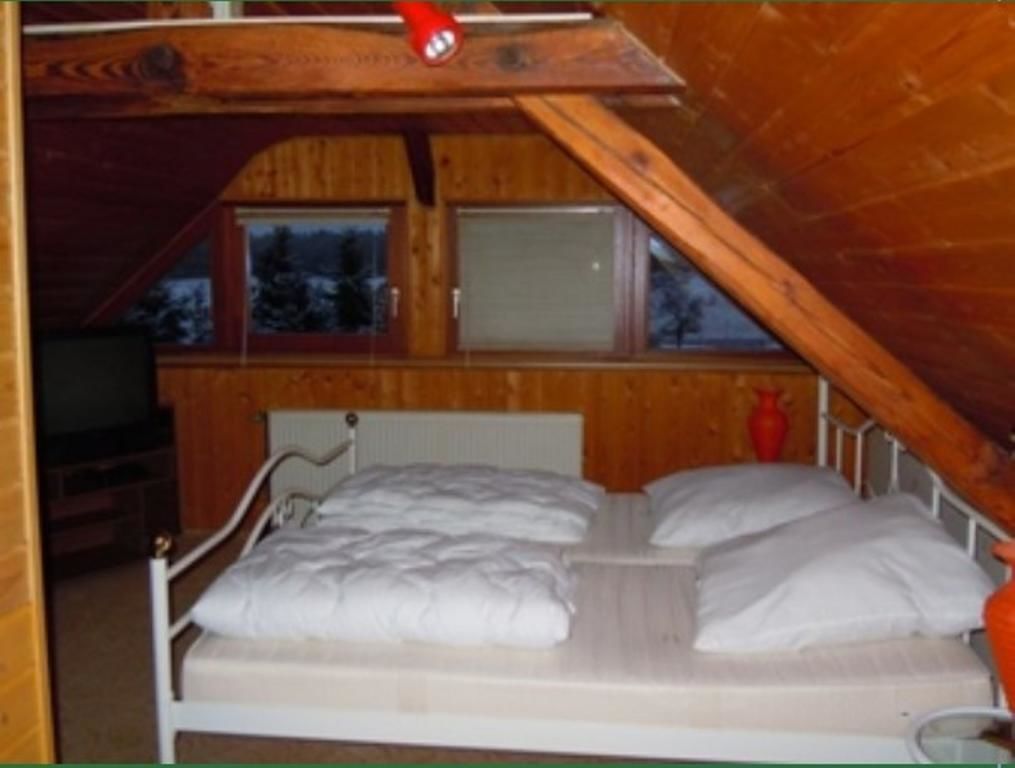 Ein kleines Schlafzimmer in einer Holzhütte mit einem Einzelbett, einem Fenster und einem roten Gegenstand an der Decke.