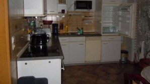 A compact kitchen with white cabinets, a microwave, and a coffee maker. - Ferienwohnung Müller (Spremberg)