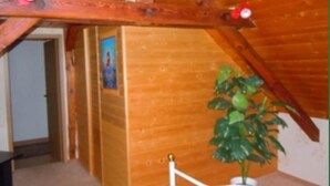A bedroom with wooden beams, a bed, a potted plant, and a door leading to another room. - Ferienwohnung Müller (Spremberg)
