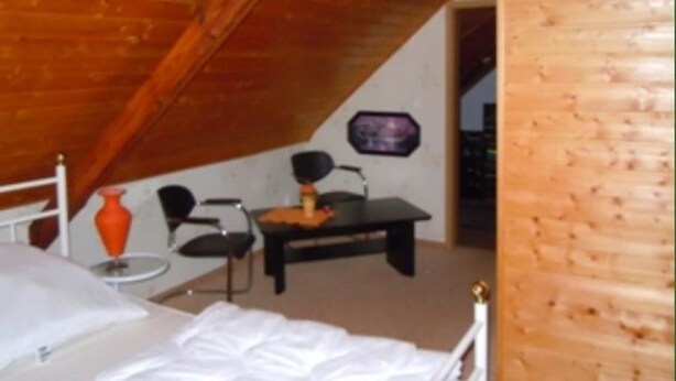 A room with a sloped ceiling, a bed, a desk, and a chair. - Ferienwohnung Müller (Spremberg)