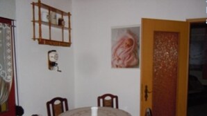 A dining area with a round table, chairs, a clock, and a door with a decorative panel. - Ferienwohnung Müller (Spremberg)
