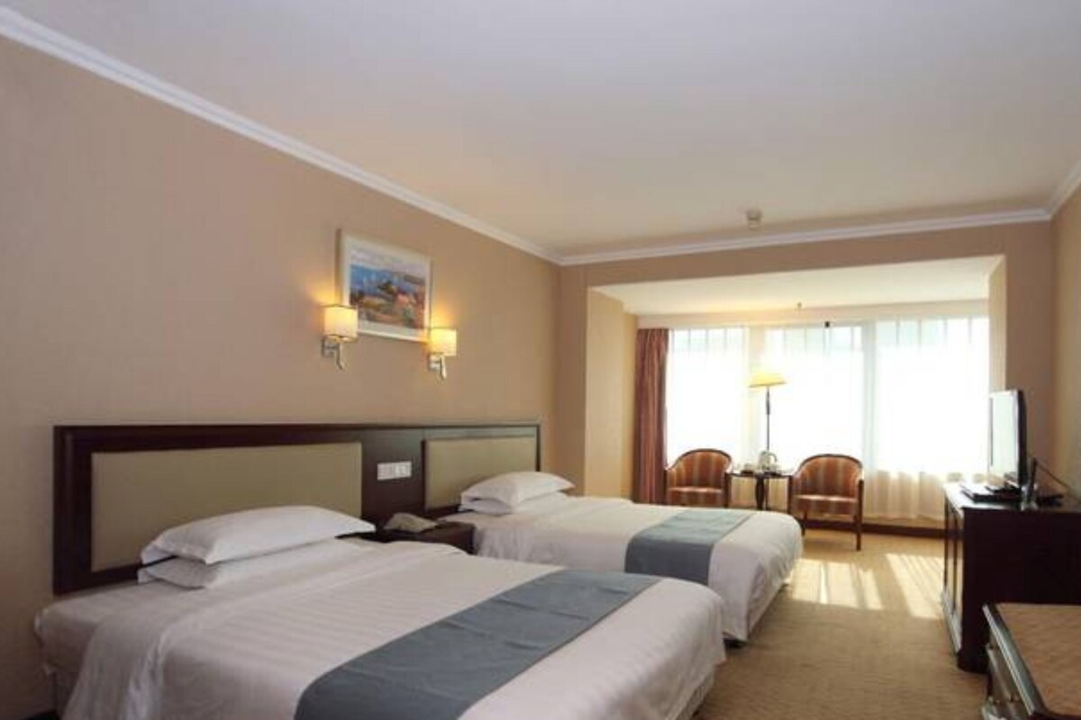 Een hotelkamer met twee bedden, een bureau, een stoel en een televisie.