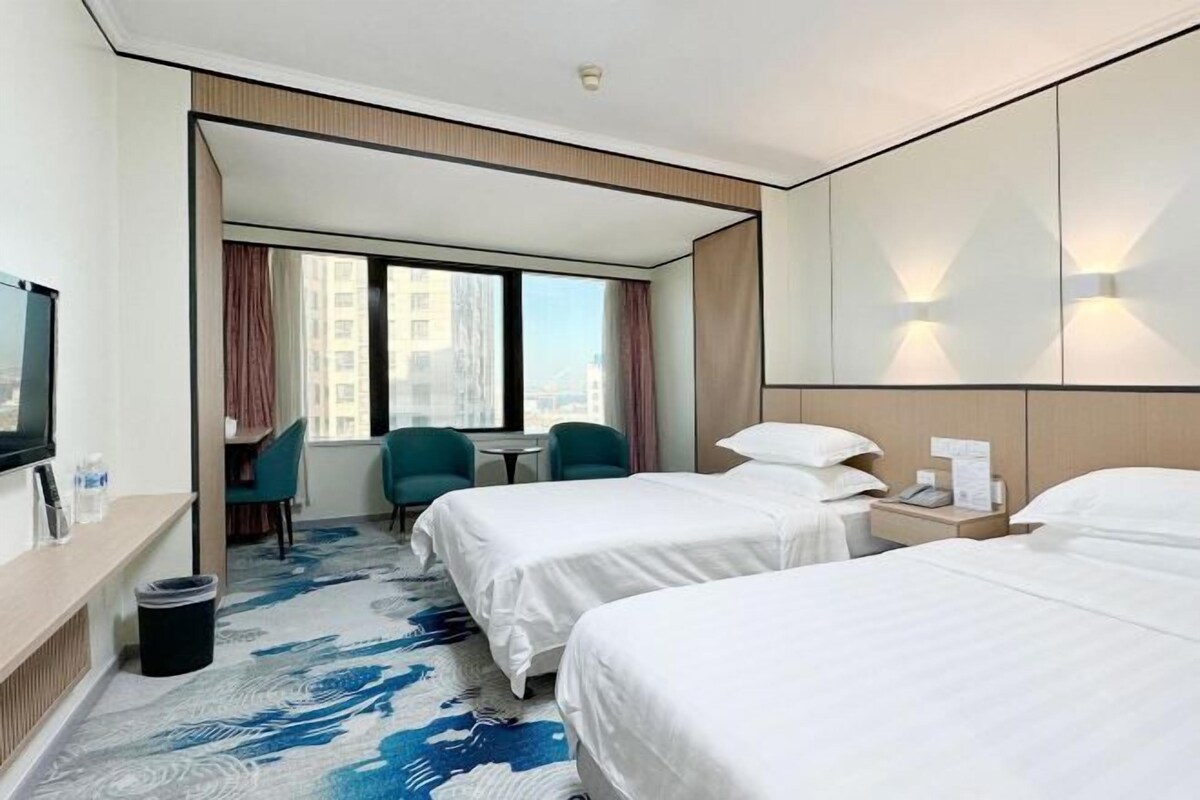 Een hotelkamer met twee bedden, een bureau, een stoel en een televisie.