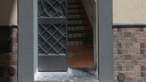 An arched entrance with a decorative sign, a metal gate, and a staircase leading inside.