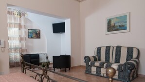 A living room with a sofa, a television, and a painting on the wall.