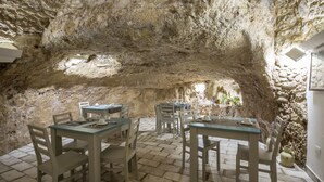 Un espace de restauration souterrain avec des murs, des tables et des chaises en pierre.